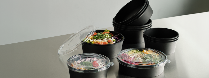 The collection consists of black paper-based trays and bowls with a functional barrier, combined with transparent lids for clear on-shelf and take-away visibility. Photo: Duni Group