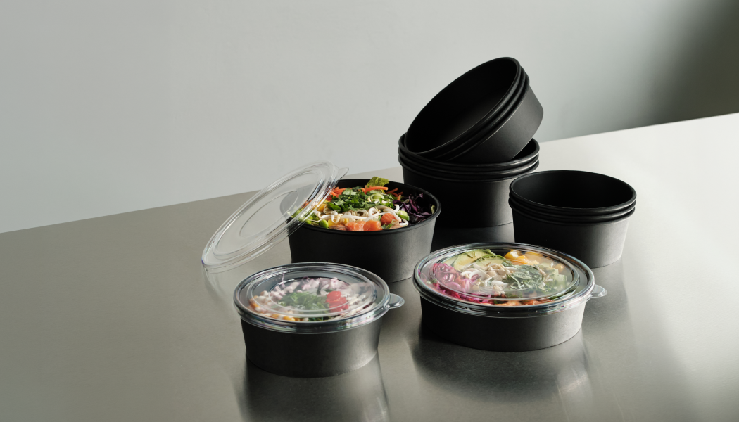 The collection consists of black paper-based trays and bowls with a functional barrier, combined with transparent lids for clear on-shelf and take-away visibility. Photo: Duni Group